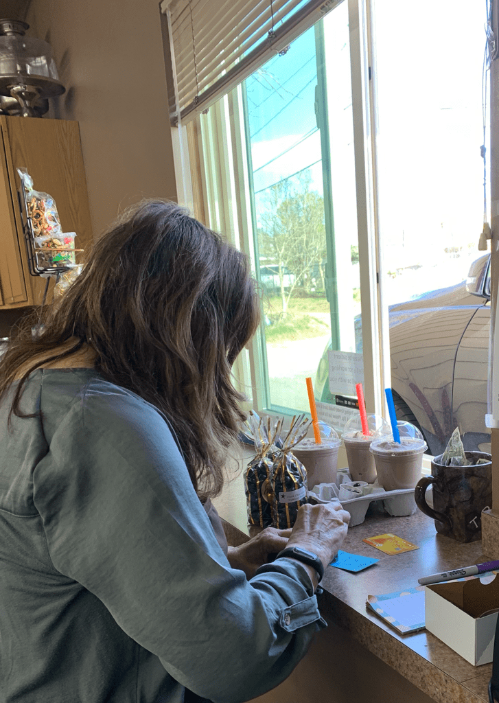 Woman serving coffee out of a drive through window